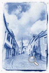 Rue principal de la Roche-Derrien, toute en pente, au loin on distigue l'église et un cycliste en tout petit qui descend.
